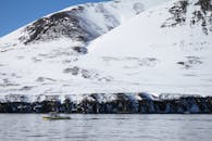 一艘孤独的船在冰冷的水域中驶向冰岛的雪山