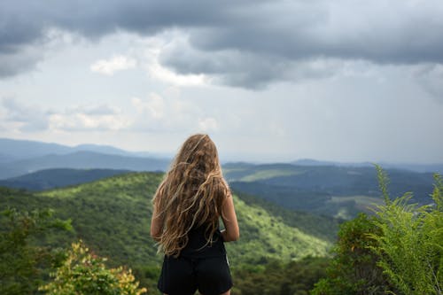 Back View of a Blonde-Haired Woman Standing on Mountain