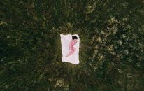 Woman in Pajamas Sleeping on White Blanket on Grass Field