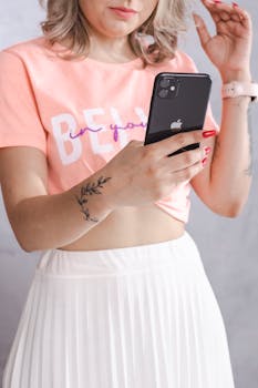 Woman in a peach top and white skirt using a smartphone indoors.