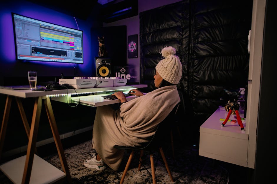 How Blackout Curtains Boost Melatonin and Deep Sleep Duration A person wrapped in a blanket working on music production in a cozy home studio setting.