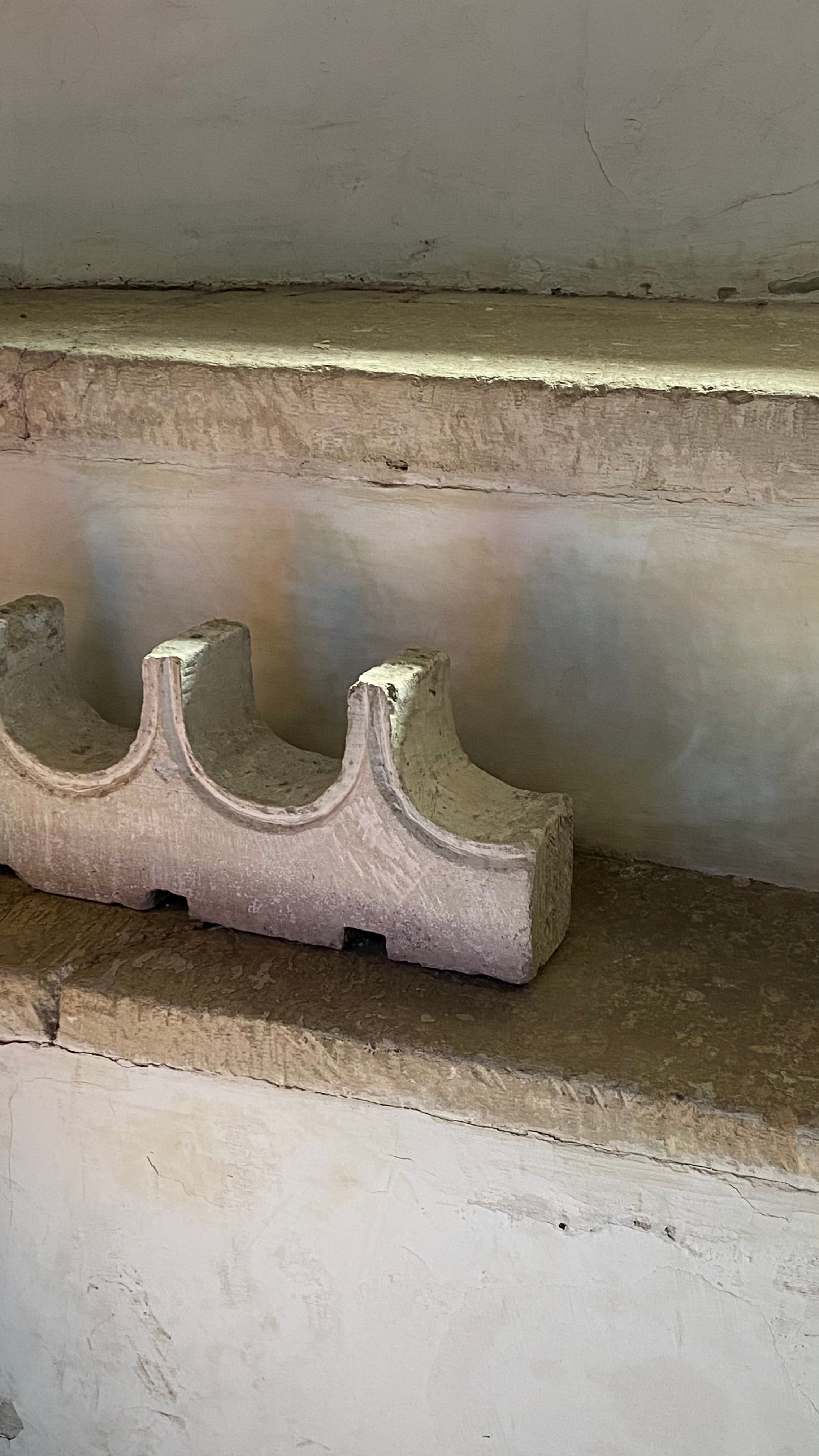 Weathered stone carving displayed on a rustic shelf with a vintage aesthetic.