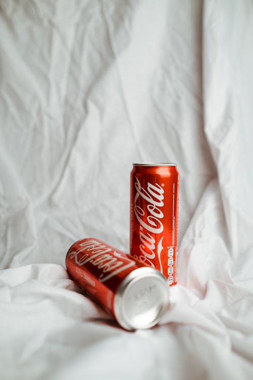 Free Coca Cola Cans on White Textile Stock Photo