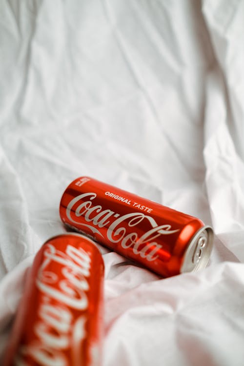 Coca Cola in Cans on White Textile