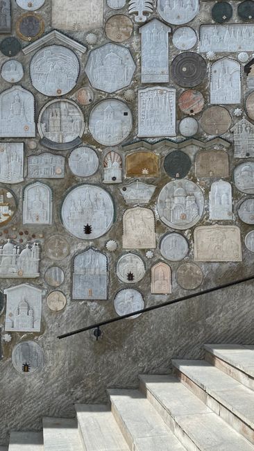 Abstract stone wall art displaying geometric shapes with artistic carvings and nearby staircase.