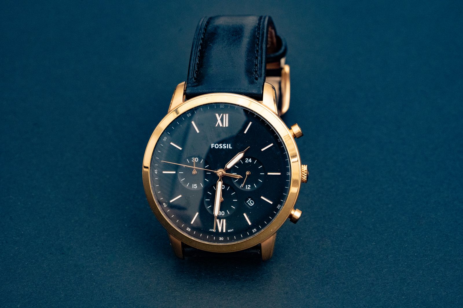 Montre de luxe femme à boîtier or rose et cadran à chiffres romains, posée sur un drapé de velours sombre
