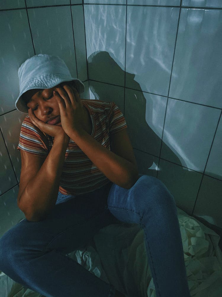 Man In White Bucket Hat Sitting On The Corner Of A Room