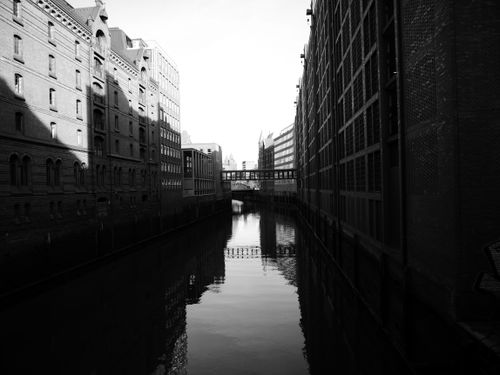 Free Black and white photo of Hamburg's canal flanked by historic buildings, showcasing reflections. Stock Photo