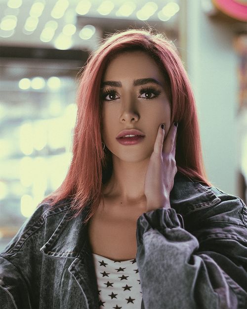 Free A striking portrait of a young woman with red hair, wearing a denim jacket, indoors. Stock Photo