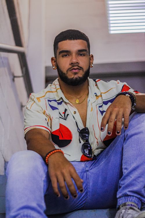 Free Young man with beard and trendy fashion sitting indoors, showcasing relaxed style. Stock Photo