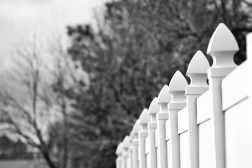Gray Scale Photo of White Fence