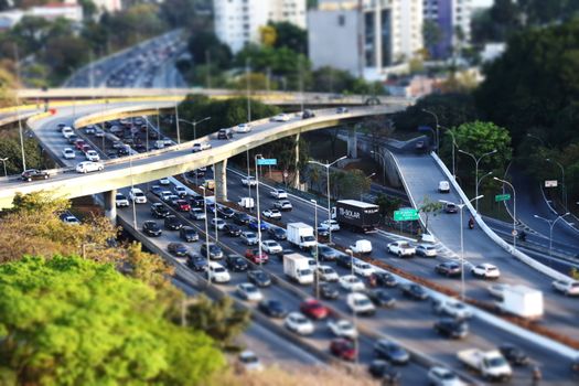Dense traffic on a multi-level urban highway with tilt-shift effect, showcasing an intricate transportation system.