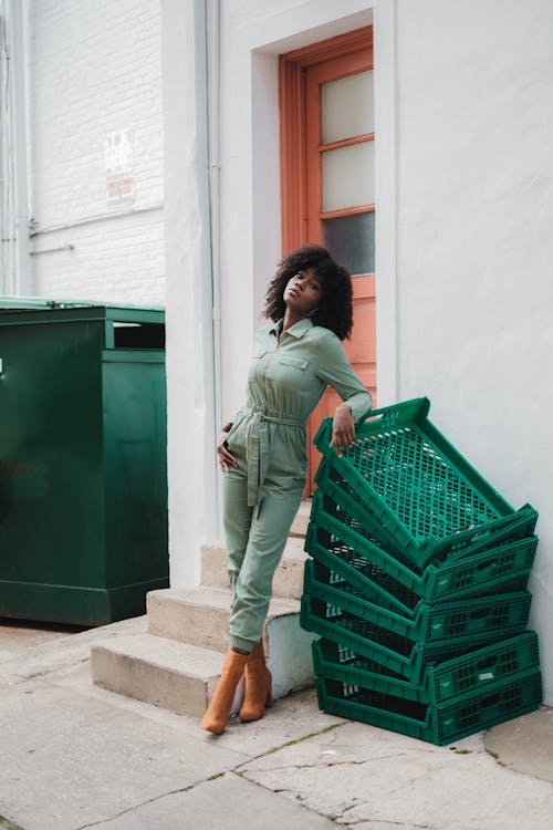 Woman in Green Jumpsuit Standing Beside Green Crates