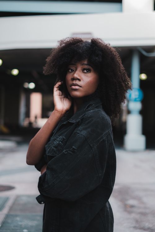 Free Stylish young woman with afro hair posing in an urban setting, exuding confidence and elegance. Stock Photo