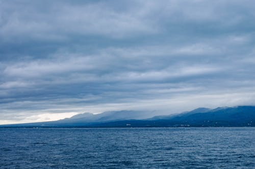 Island Across Body of Water Under Cloudy Sky