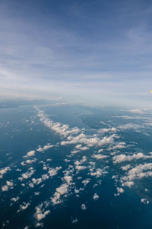 Free Breathtaking aerial view of serene clouds floating over the vast blue ocean on a clear day. Stock Photo