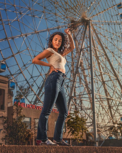 Woman in White Crop Top and Blue Denim Jeans Standing on Concrete Surface