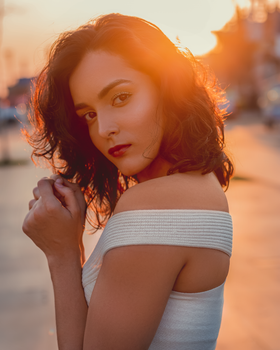 Elegant backlit portrait of a woman at sunset exuding charm and beauty.