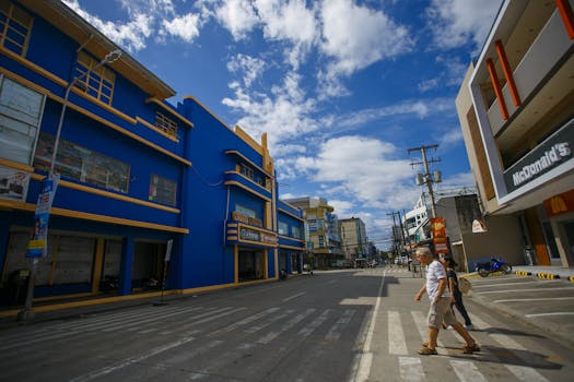 阳光明媚的天空下，充满活力的城市街道上，行人过马路，建筑丰富多彩