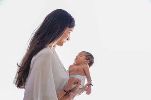 Free Woman in White Robe Carrying Baby Stock Photo