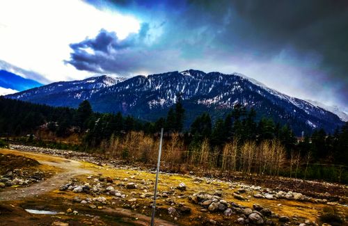 Free Beautiful snowy mountain landscape with cloudy skies and rocky terrain. Stock Photo