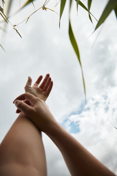 Free Arm Raised Up in the Air Under White Clouds Stock Photo