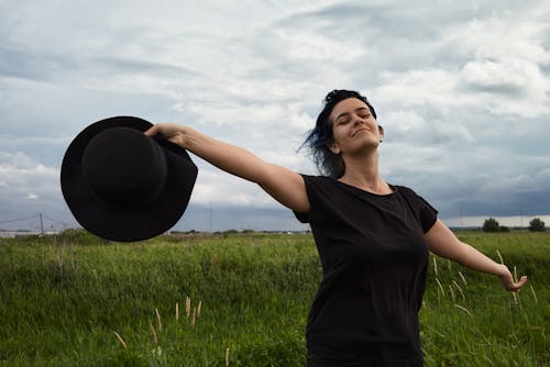 A Woman in Black  Shirt Holding a Black Hat