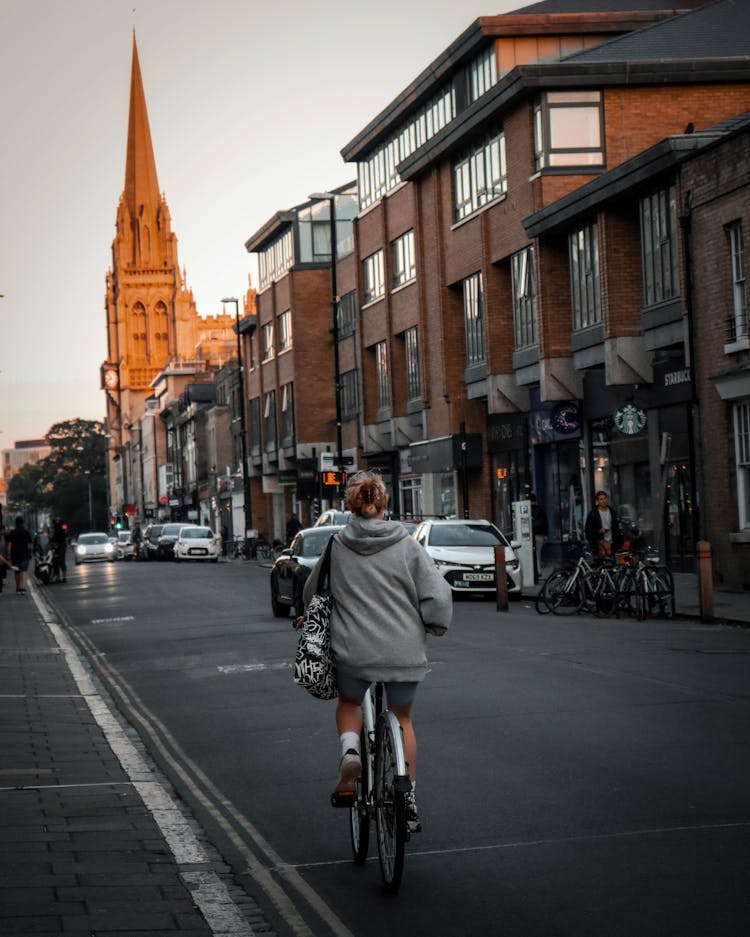 Woman Wearing Gray Hoodie Riding Bicycle On The Street