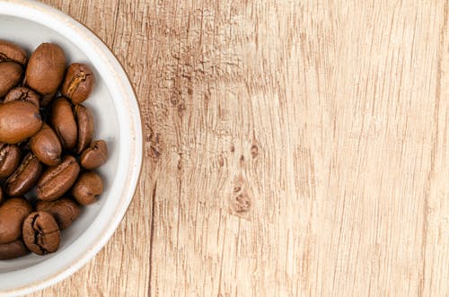Free Coffee Beans on White Ceramic Bowl on Top of Brown Wooden Surface Stock Photo