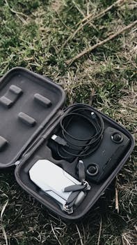 Compact drone and accessories in a protective case on green grass, representing modern technology and portability.