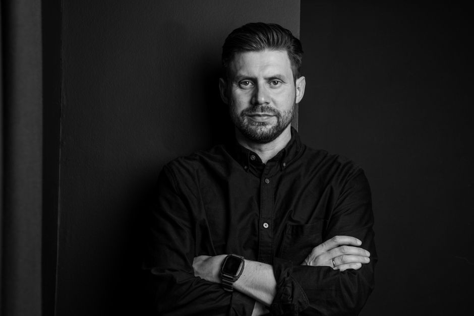 Withings ScanWatch 2 vs Apple Watch: Health Monitoring Showdown (2024) Monochrome portrait of a man with beard and crossed arms in studio setting.
