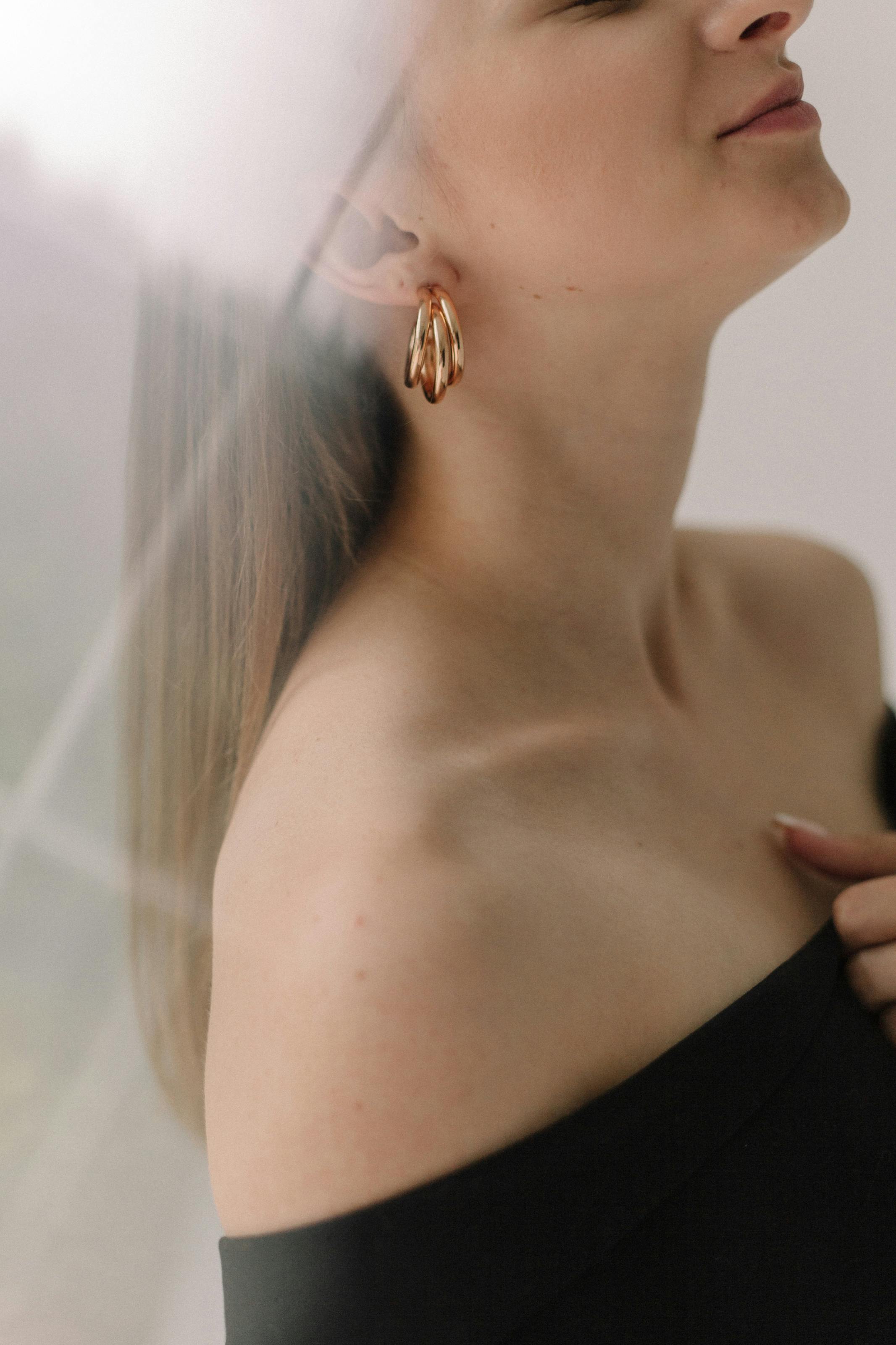 close up shot woman in black tube top wearing gold earrings