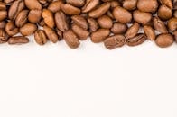 白色背景上特写的烘焙咖啡豆，非常适合咖啡相关设计