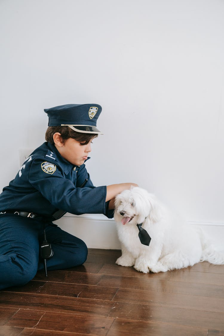 A Boy In A Police Costume Playing With His Dog