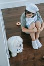 Woman in Gray Long Sleeve Shirt Sitting Beside White Long Coated Small Dog