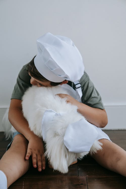 Free Photo of a Boy with a Chef Hat Playing with a Dog Stock Photo