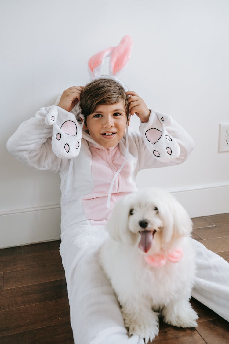 Boy Wearing White Onesie Rabbit Costume Sitting On Floor 