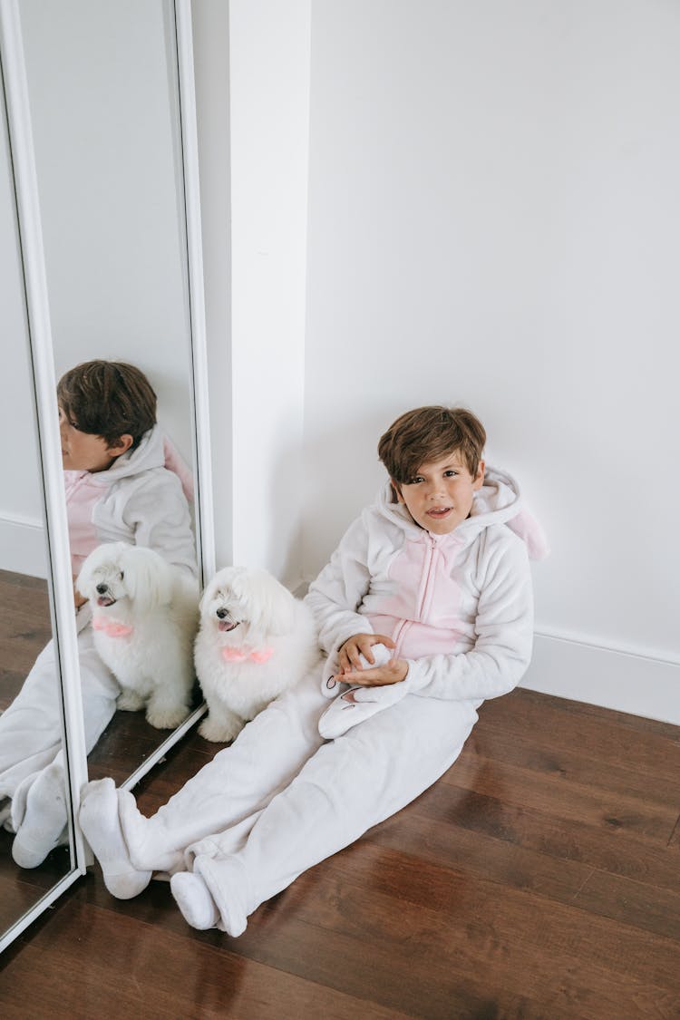 A Kid In A Costume Sitting On The Floor With His Dog