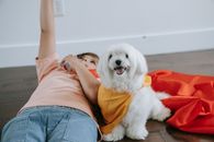 A Boy Lying Down on the Floor and a Dog in a Cape