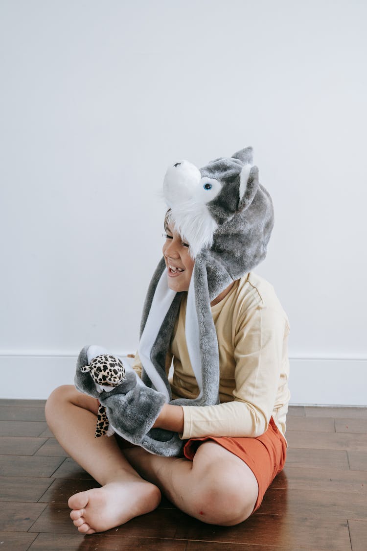 Boy Sitting On Floor With Plush Animal  Hat