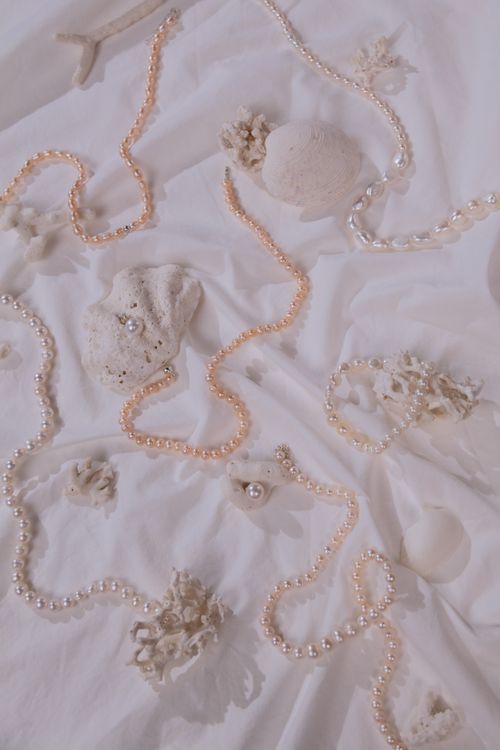 Free Aesthetic arrangement of pearls and corals on white textile, offering a sense of calm elegance. Stock Photo