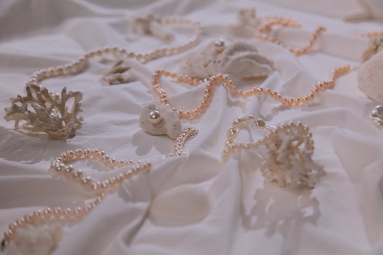 Photograph Of Pearl Necklaces On A White Cloth