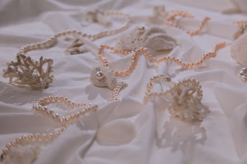 Free Sophisticated pearl necklaces elegantly draped on coral, signifying luxury and nature's beauty. Stock Photo
