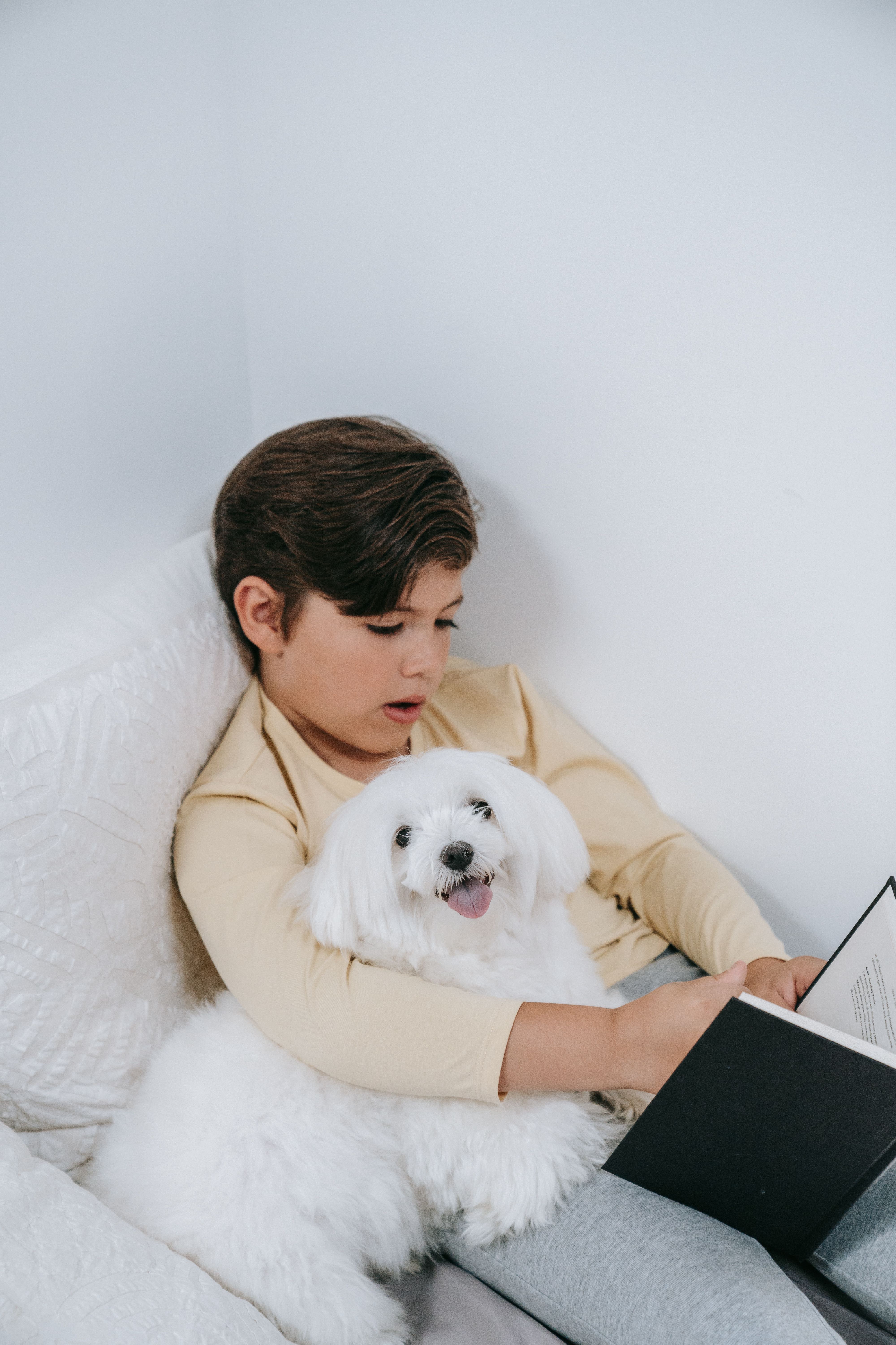 A small child reading a book to a dog