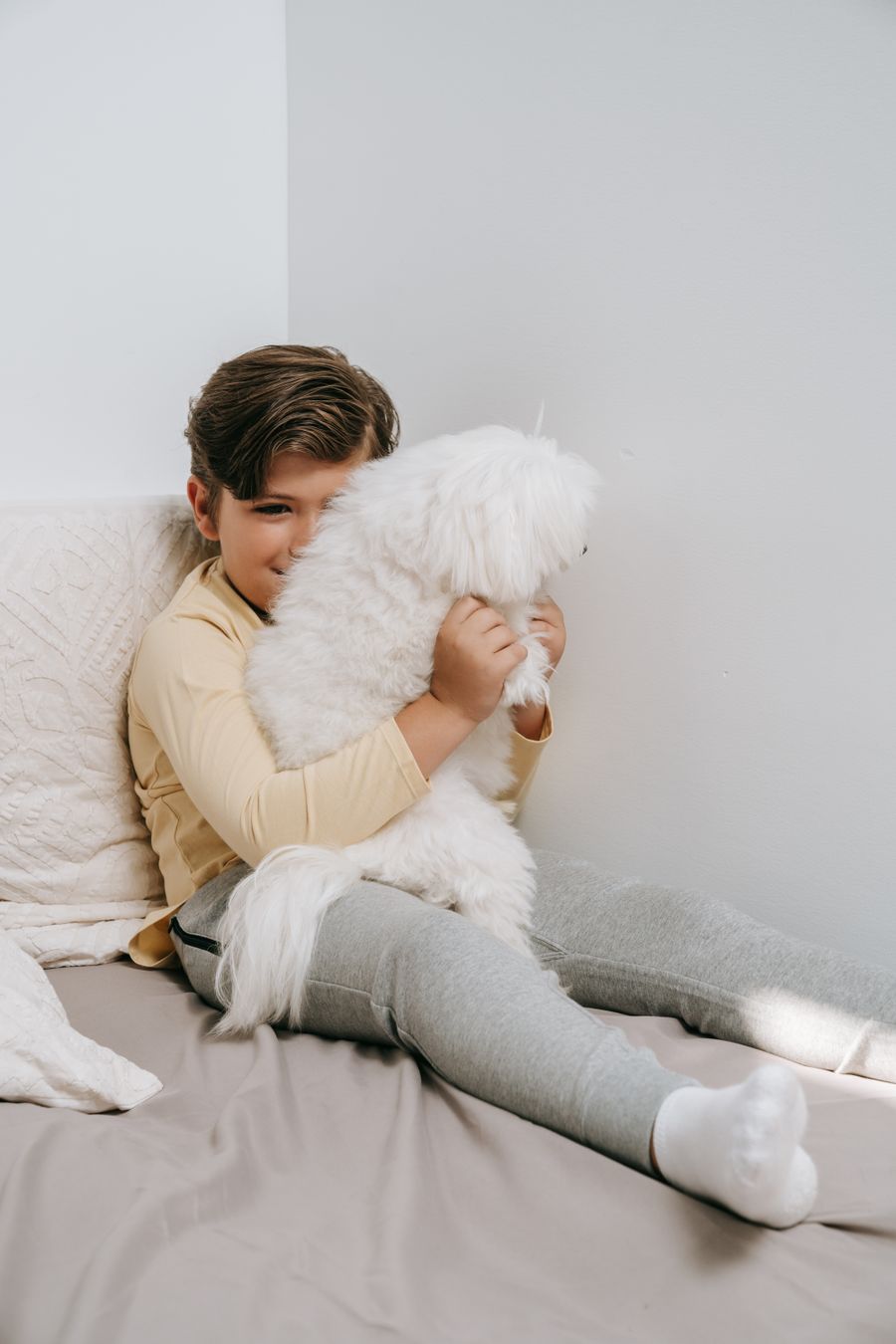 Boy hugging a fluffy white dog indoors