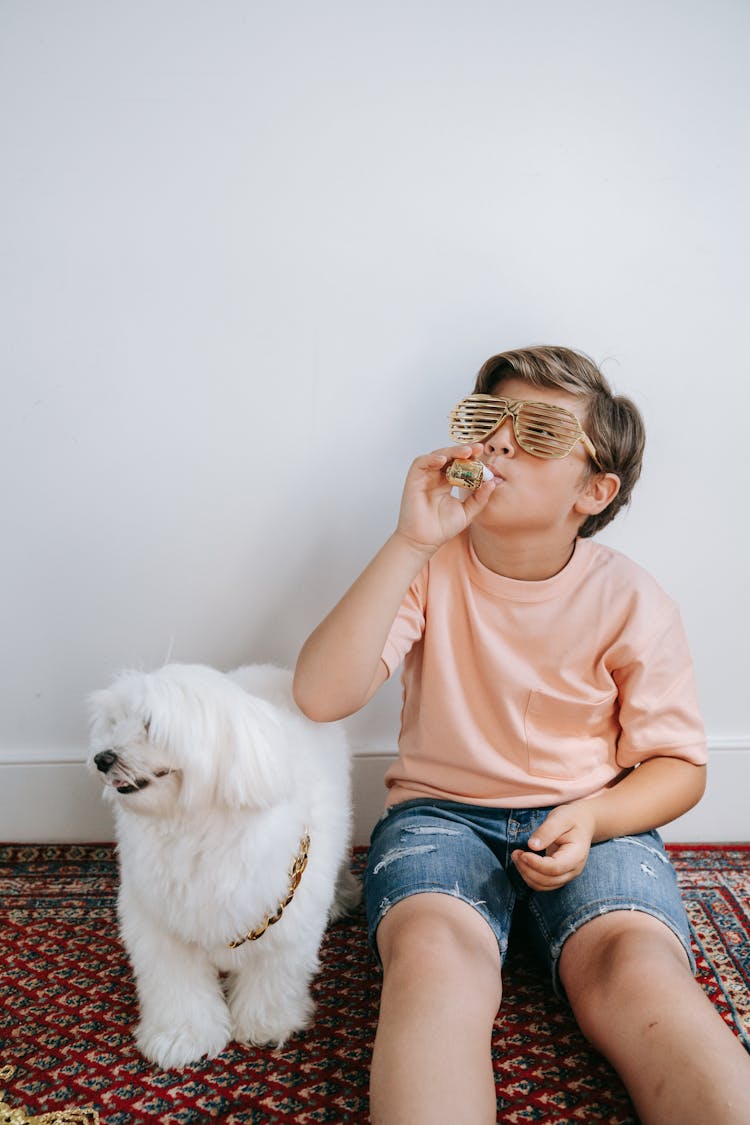 Boy Sitting On Carpet Beside A Dog