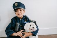 Boy in Blue and White Cap Holding White Long Coated Small Dog