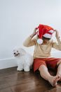 Woman in Beige Long Sleeve Shirt Sitting on Red Chair Beside White Long Coat Small Dog