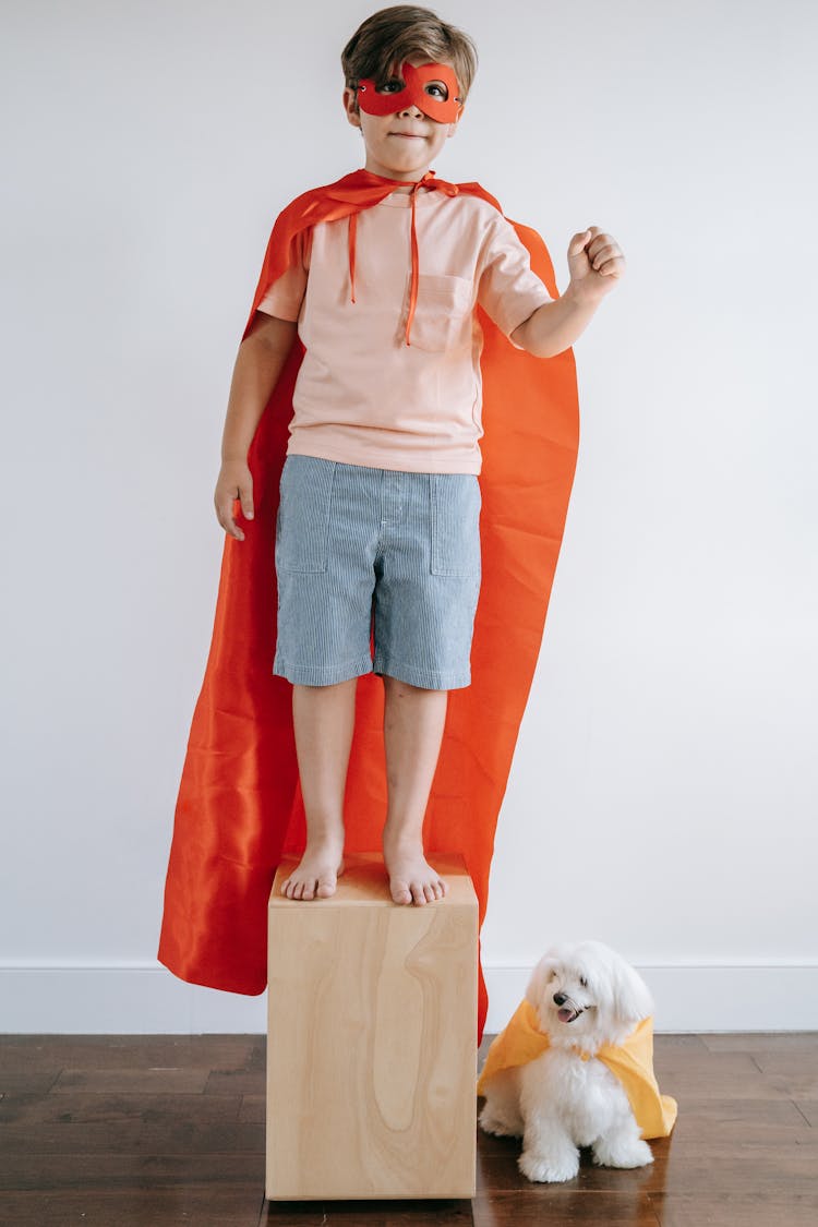 A Boy Wearing A Cape With His Dog