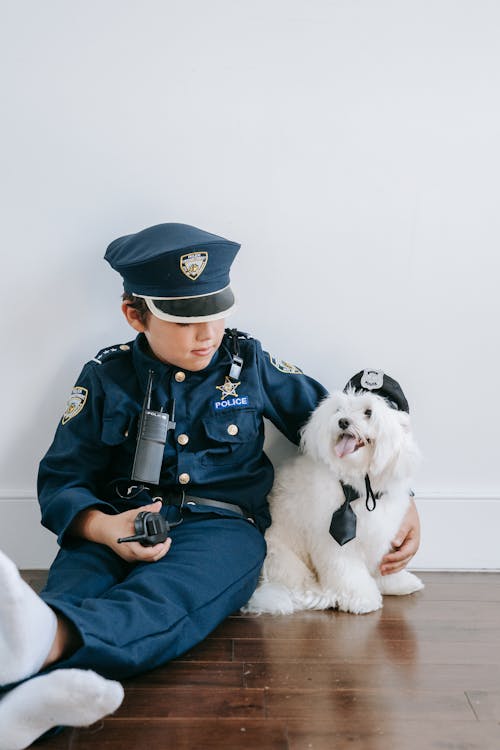 Free Man in Blue and White Jacket Holding Black and White Long Coated Small Dog Stock Photo